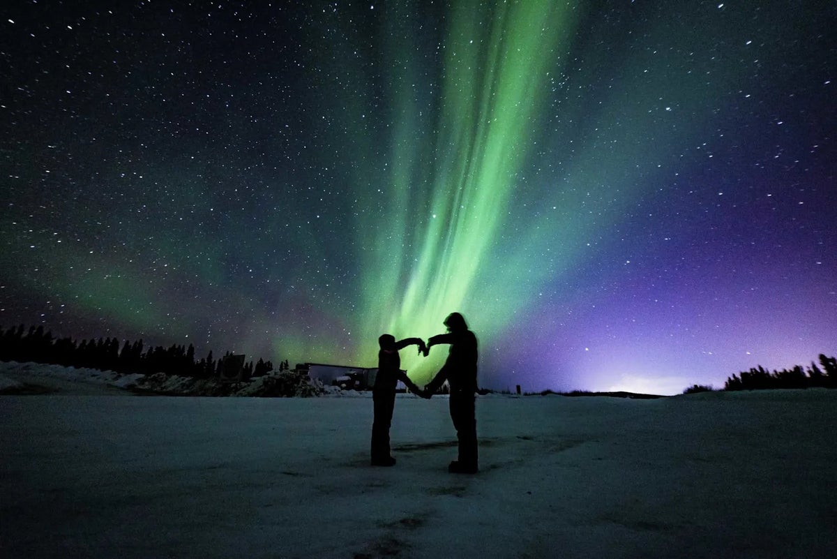 https://gti.images.tshiftcdn.com/7250934/x/0/two-people-form-a-heart-shape-under-the-northern-lights-in-the-snowy-wilderness-of-iceland-on-a-clear-winter-night.jpg?crop=1.91%3A1&fit=crop&width=1200